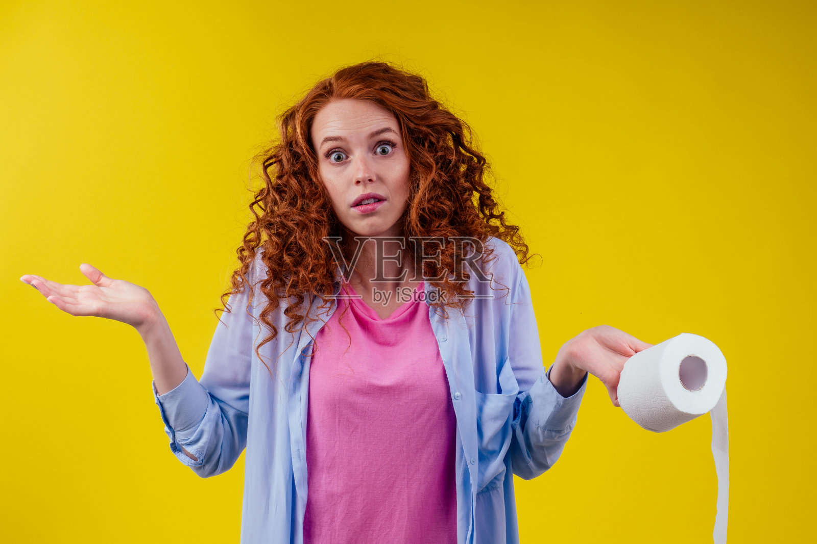 美丽的卷发红发姜女手持生态卫生纸卷在黄色的背景色照片摄影图片