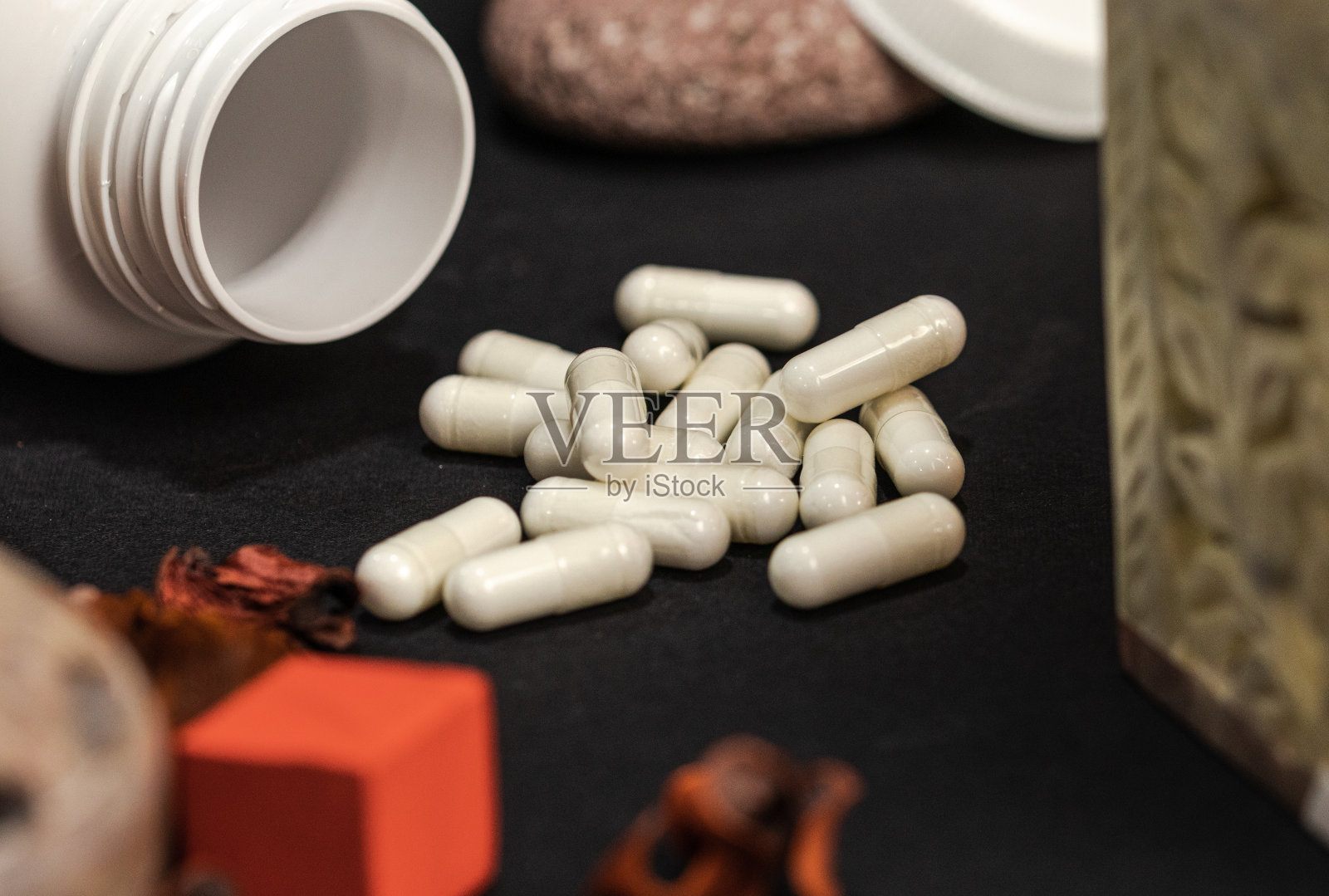 白色的补品瓶子，黑色的背景上有白色的胶囊照片摄影图片