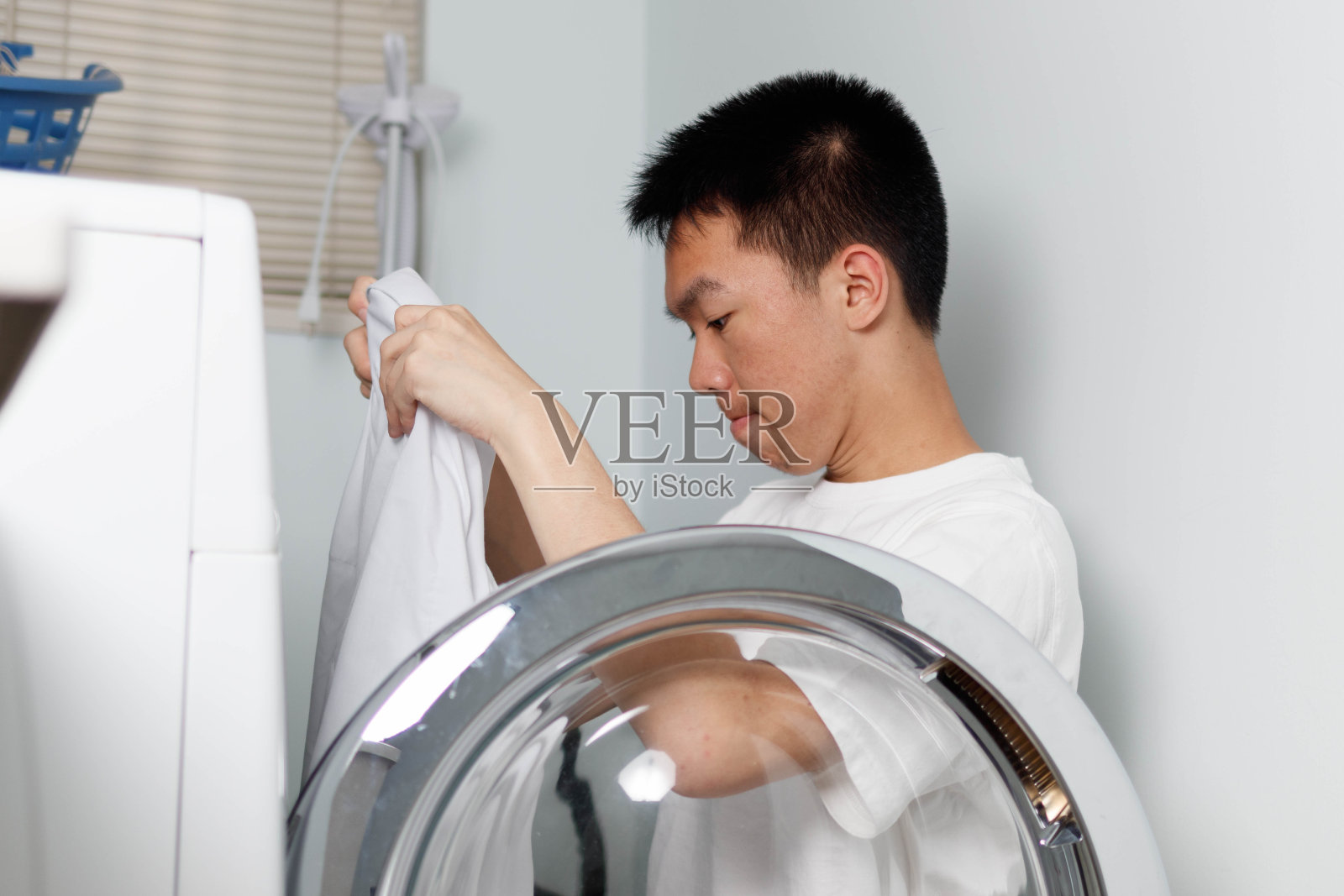 十几岁的男孩在洗衣机里洗衣服照片摄影图片