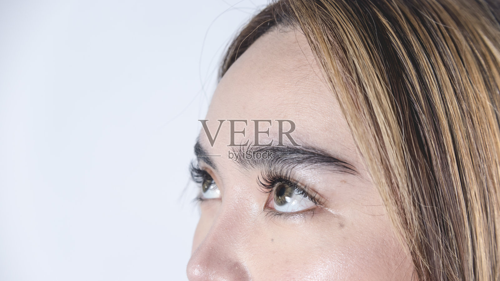 一个20多岁的菲律宾女人的前额和眼睛的特写。长睫毛，戴琥珀色隐形眼镜。照片摄影图片