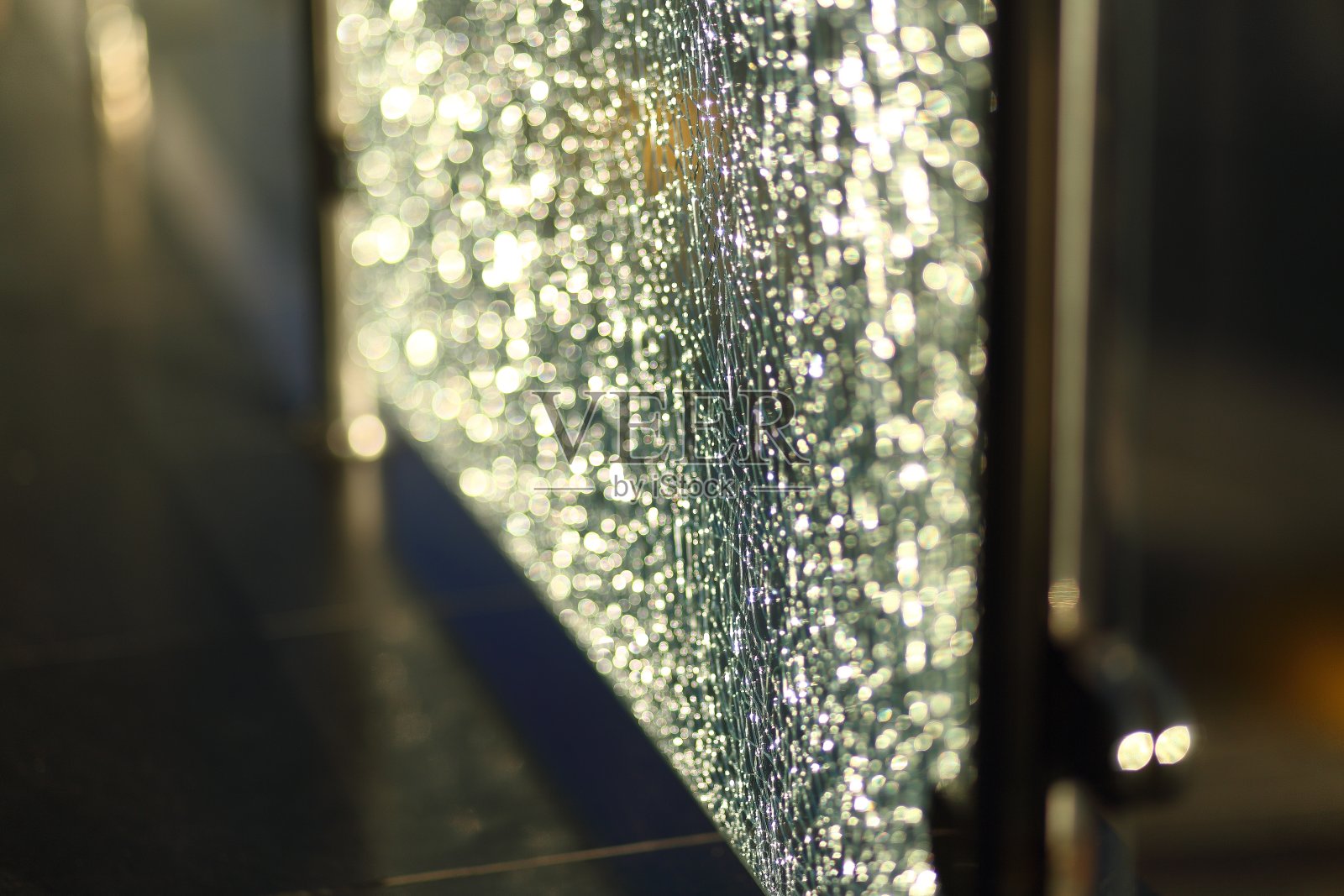 城市中破碎的玻璃栅栏的特写。阳光透过玻璃照射进来。散景。照片摄影图片