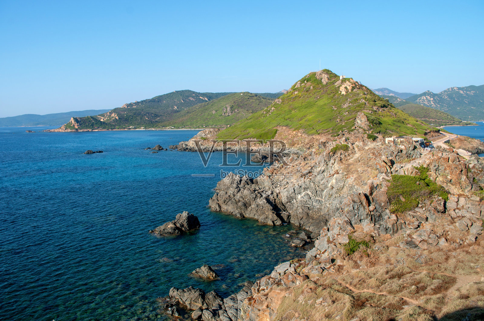 阳光普照的山丘和法国海边的岩石海岸。照片摄影图片