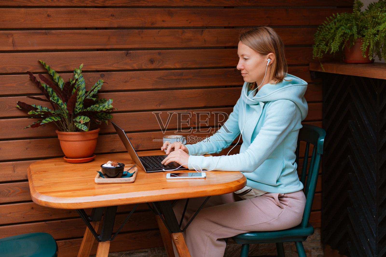 在街上的咖啡店里用手机和笔记本电脑工作的快乐企业家照片摄影图片