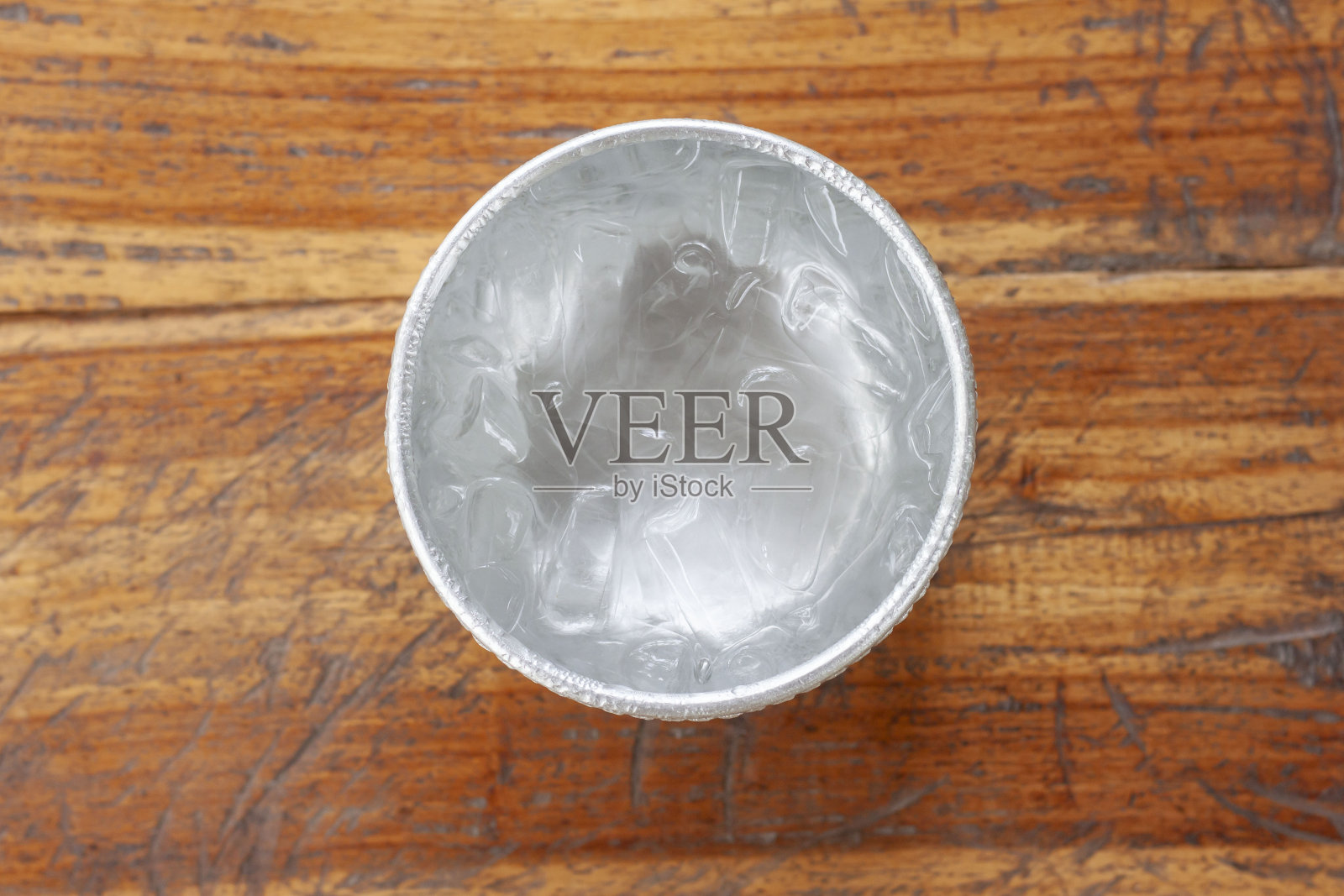 木桌上的水勺里的冰块的俯视图。照片摄影图片