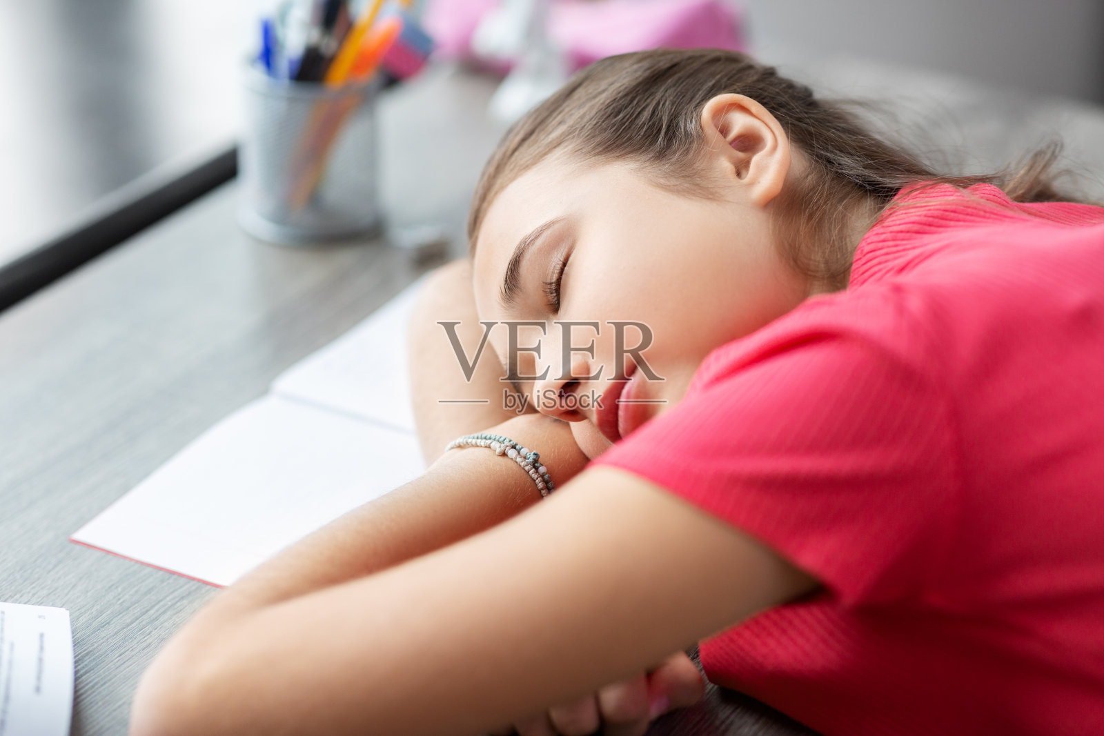 疲惫的女学生睡在家里的桌子上照片摄影图片