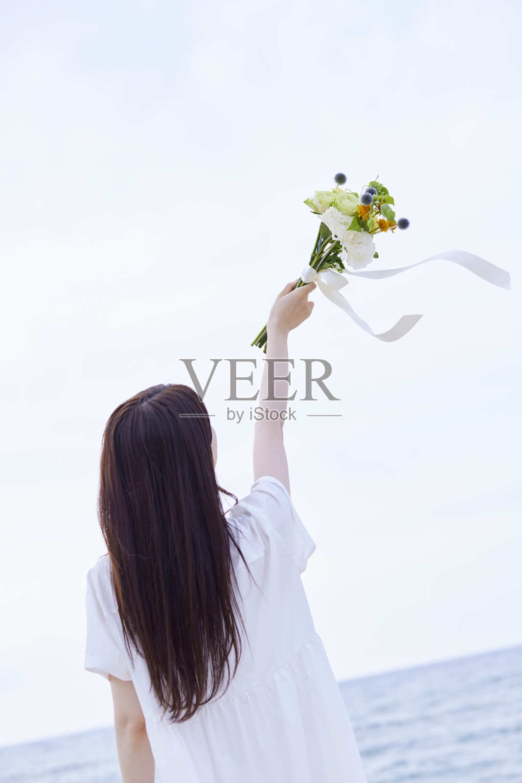 年轻的日本女子穿着裙子，手持花束照片摄影图片