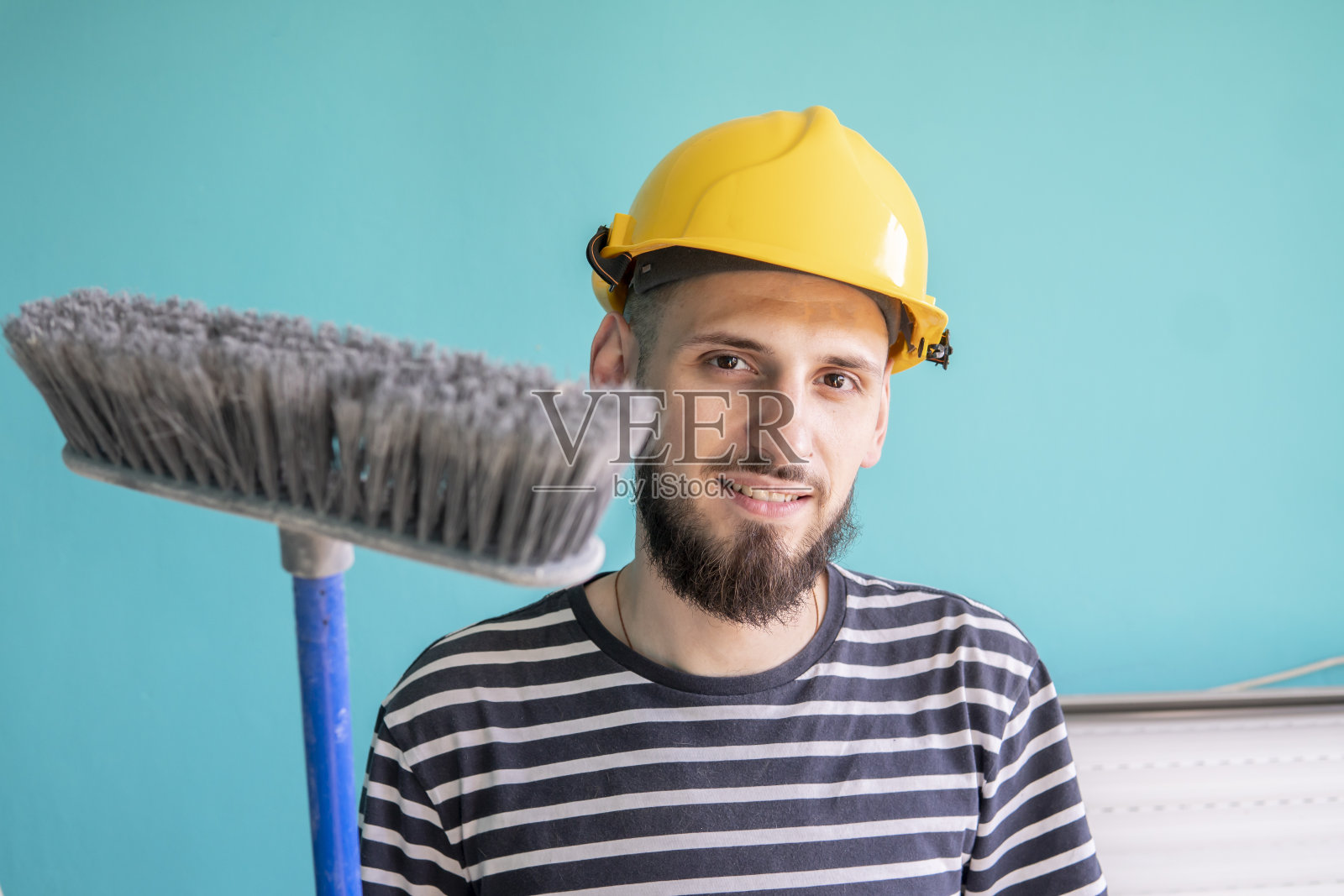 白人，修理工，手里拿着扫把。蓝色背景。进行中的工作照片摄影图片