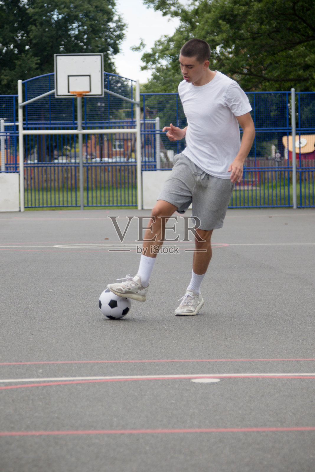 一个19岁的少年在公园里踢足球照片摄影图片