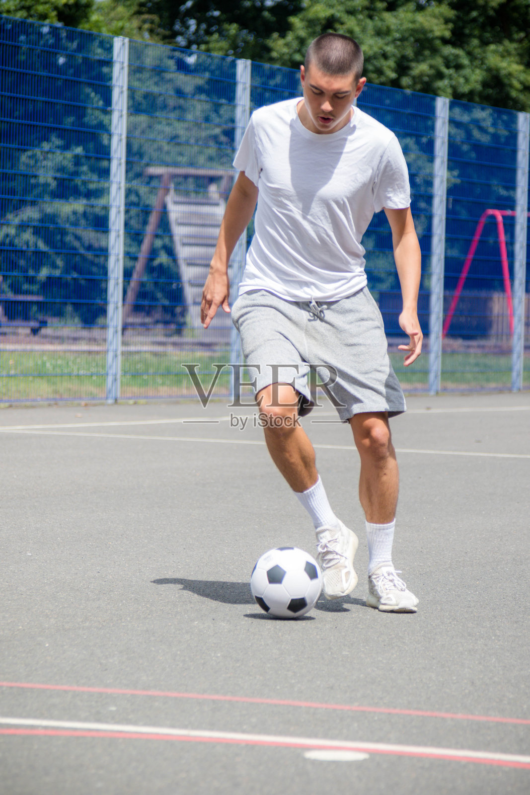 一个19岁的少年在公园里踢足球照片摄影图片