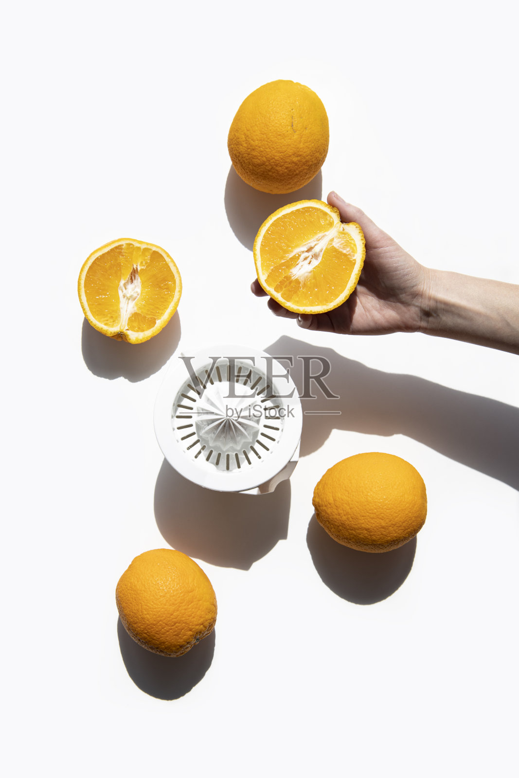 在白色背景下，女性用手从碗里的橙子中挤出果汁。俯视图，平铺照片摄影图片
