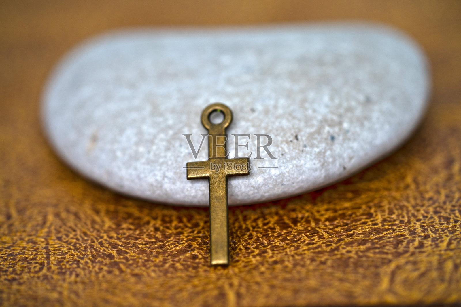 金属十字架pandant在灰色卵石与棕色皮革背景照片摄影图片