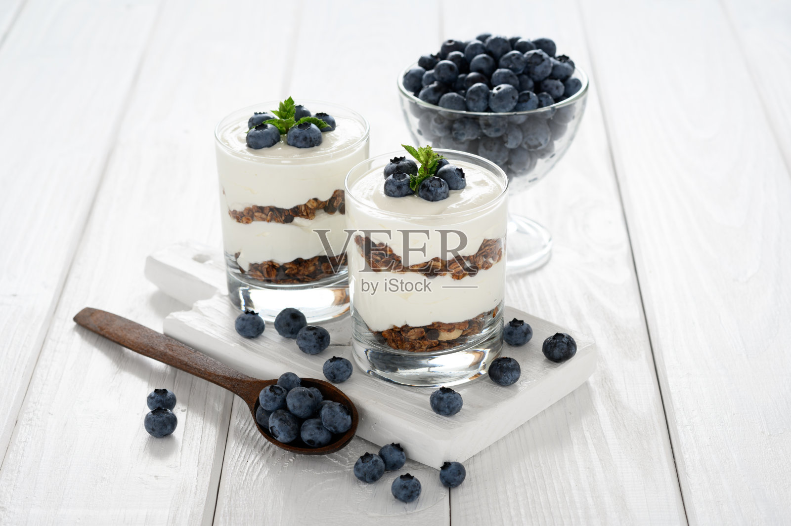 甜点，白木色背景下的白干酪，新鲜蓝莓和格兰诺拉麦片。照片摄影图片