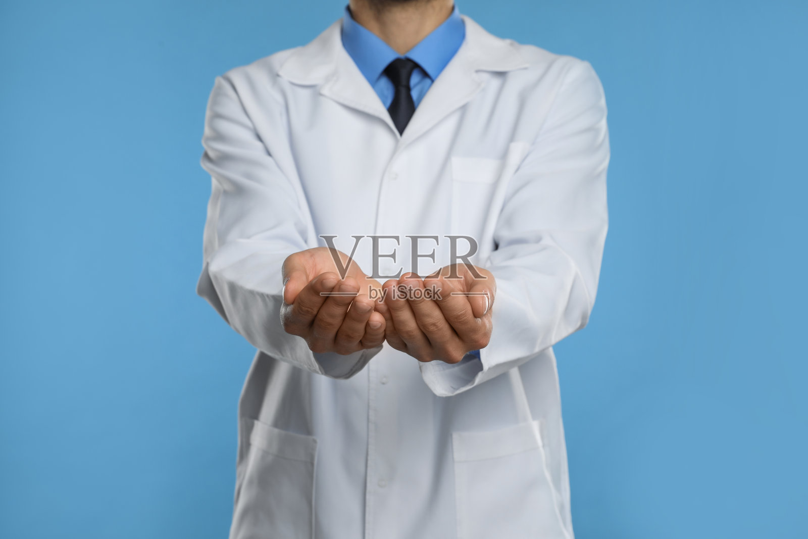 牙医拿着淡蓝色背景的东西，特写照片摄影图片