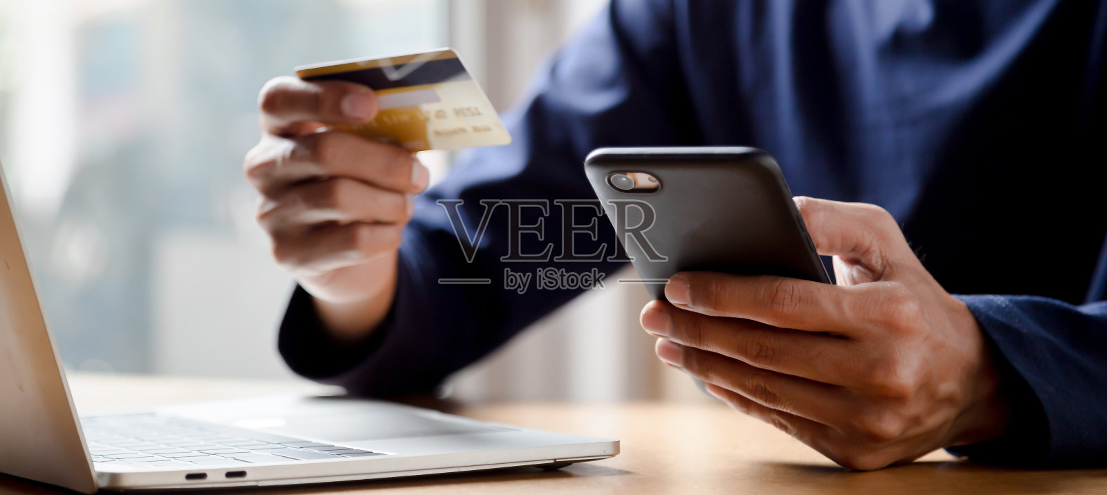 男子持有信用卡和使用智能手机在家里网上购物电子商务网上银行花钱工作从家里的概念。照片摄影图片