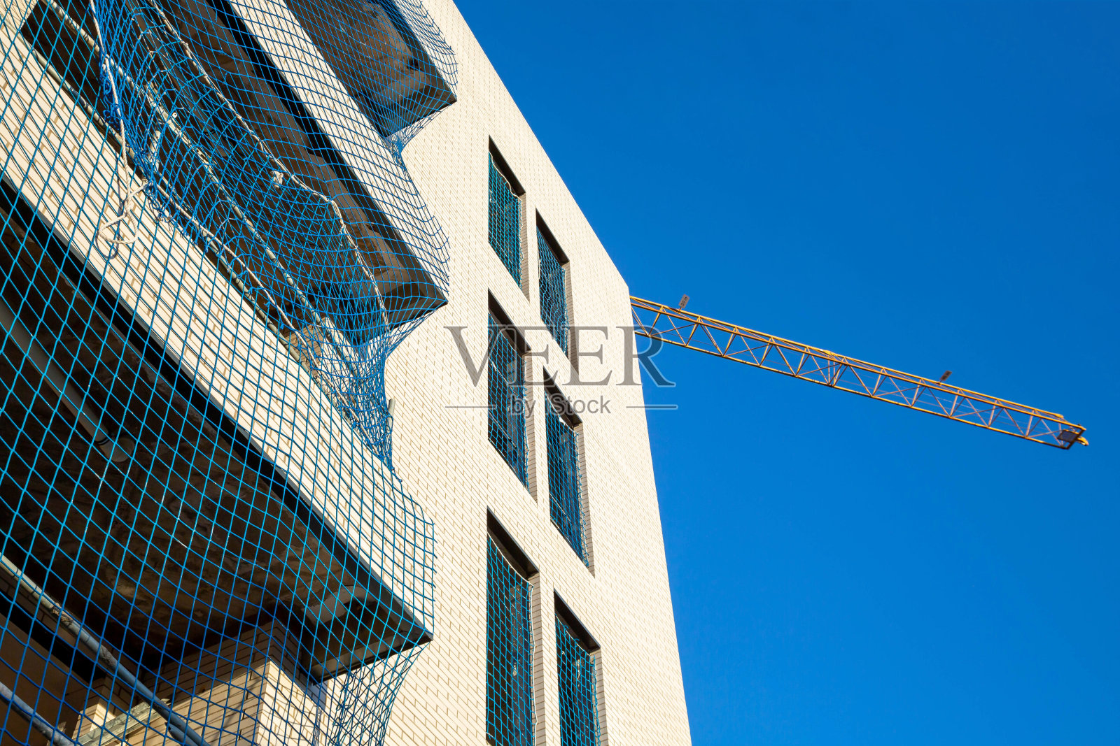 在蓝色的背景中，有阳台和起重机臂的建筑碎片。照片摄影图片