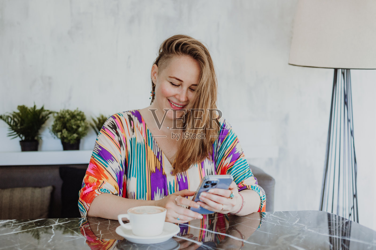 美丽的年轻女子坐在家里，浏览图片的智能手机，专注于设备屏幕照片摄影图片