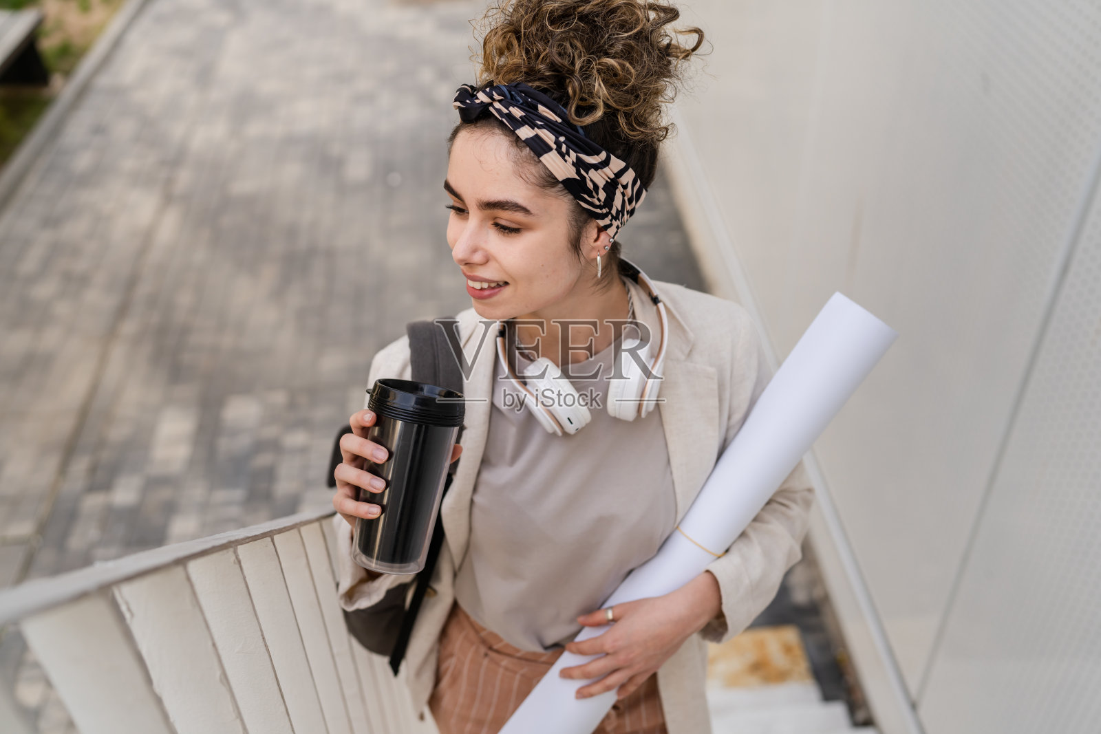 一个女人年轻的成年白人女学生背包站立或走在大学大楼前与纸和咖啡户外在明亮的日子快乐的微笑真实的人复制空间照片摄影图片