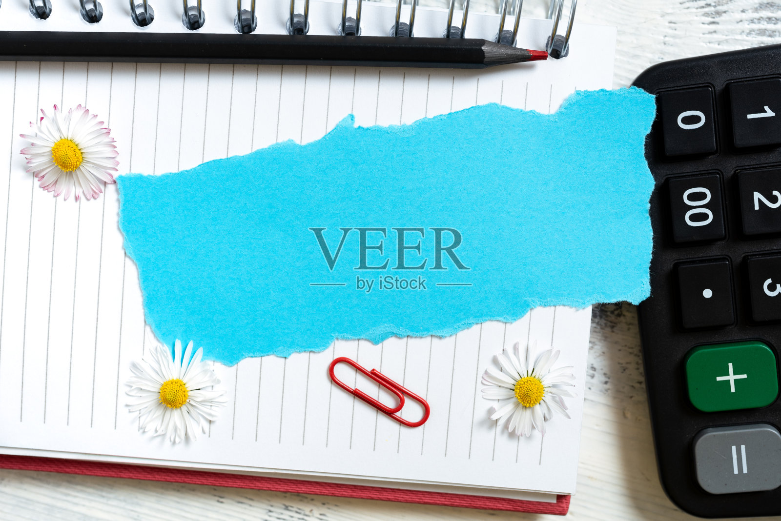 重要的信息写在带花的笔记本上的破纸上，铅笔和夹子在桌子上用计算器。关键信息记事本与植物和回形针。照片摄影图片