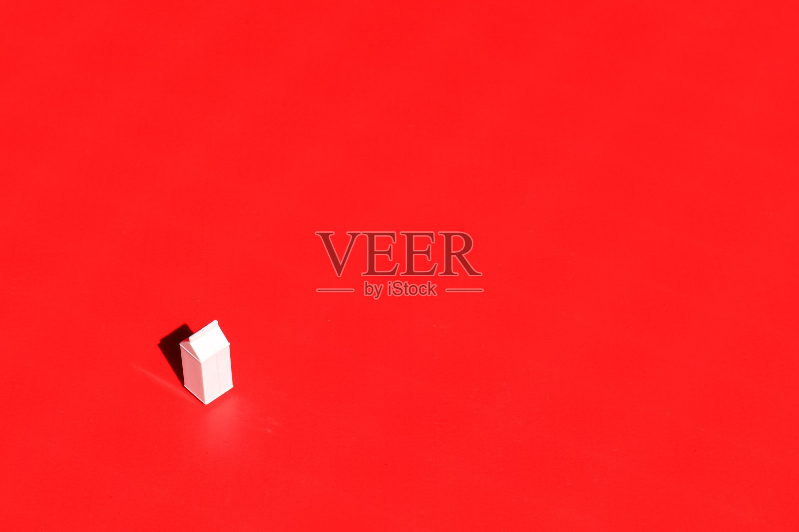 红色背景的牛奶容器。照片摄影图片