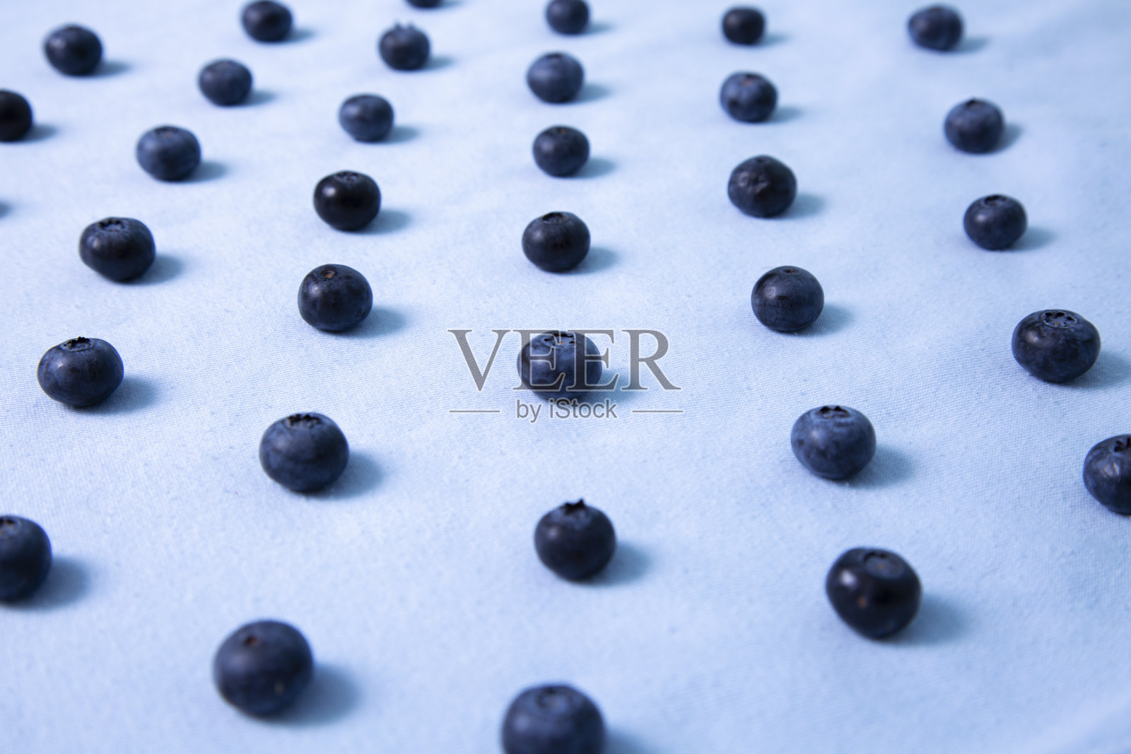 蓝莓排列在蓝色背景上照片摄影图片