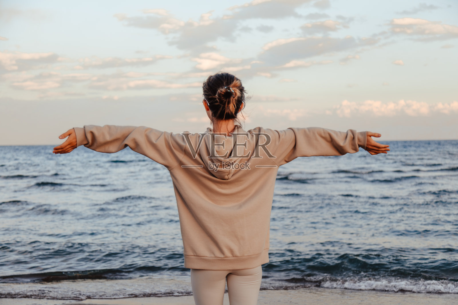 放松的女人伸展手臂在沙滩上呼吸新鲜空气，自由的概念照片摄影图片