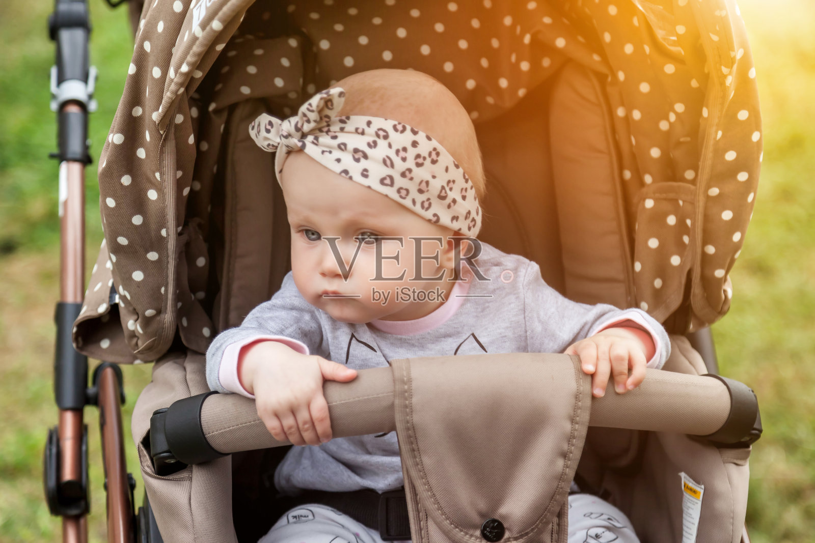 肖像悲伤，沉思，情绪，八个月大的蓝眼睛的女孩坐在婴儿车望向别处，等待父母照片摄影图片