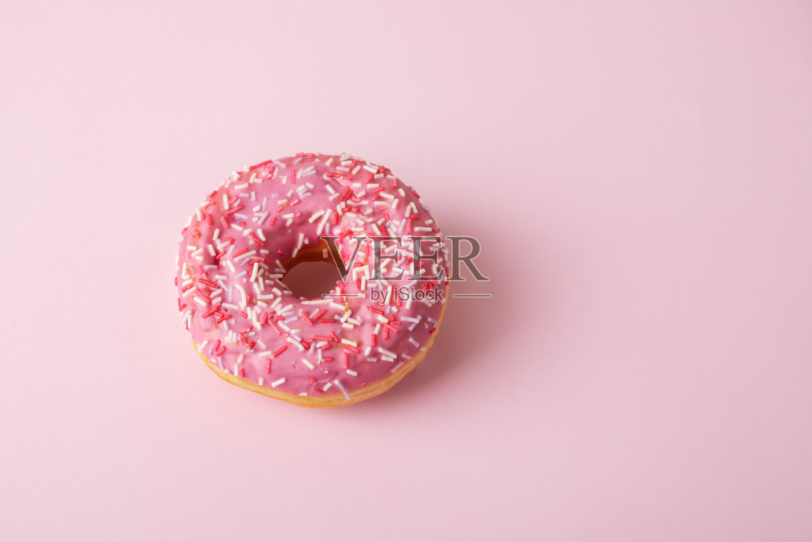 粉色甜甜圈，上面撒有糖果屑照片摄影图片