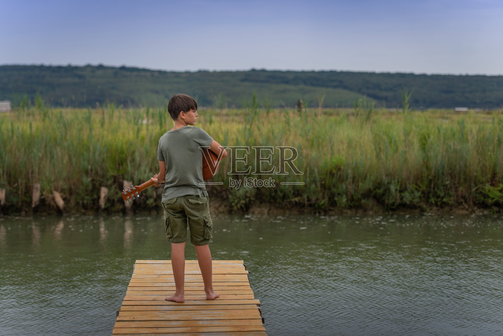 一个拿着吉他的人在码头上。照片摄影图片