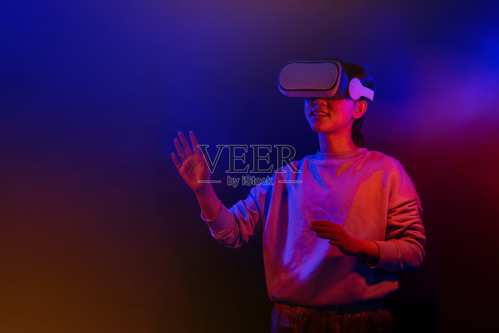 青少年与虚拟现实眼镜上的蓝色和红色的背景。照片摄影图片