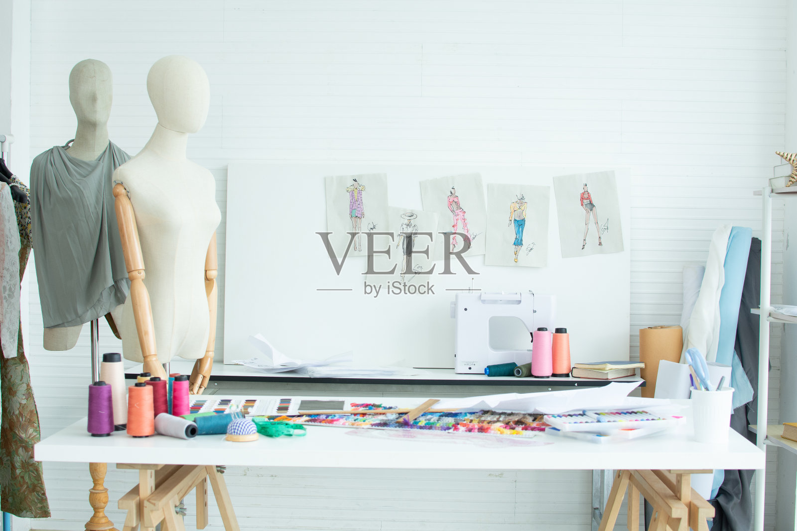 室内裁缝店或没有人的房间背景，桌子上有人体模型、衣服、线、缝纫机，墙上有服装图案纸。生活方式和小企业的概念。照片摄影图片