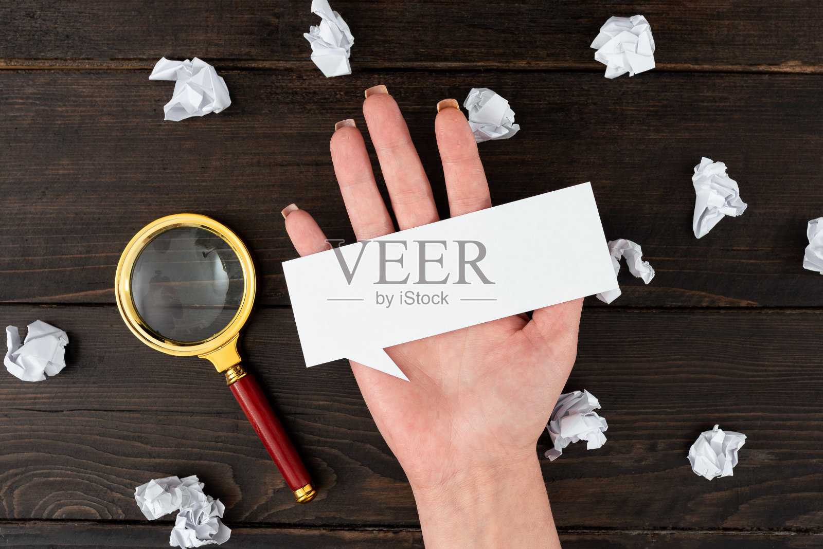 商人的手与思想泡沫表和放大镜包围皱巴巴的文件在桌子上。女人拿着纸，为商业品牌提供复印空间。照片摄影图片