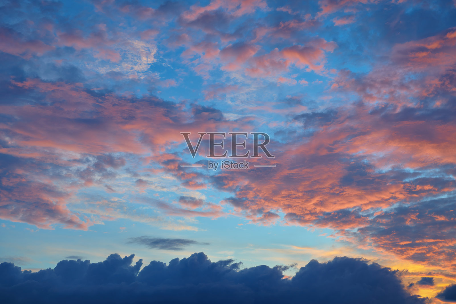 戏剧性的日落和日出天空。傍晚的天空，积云被夕阳照亮。夏天的天空飘着卷曲的红云。照片摄影图片