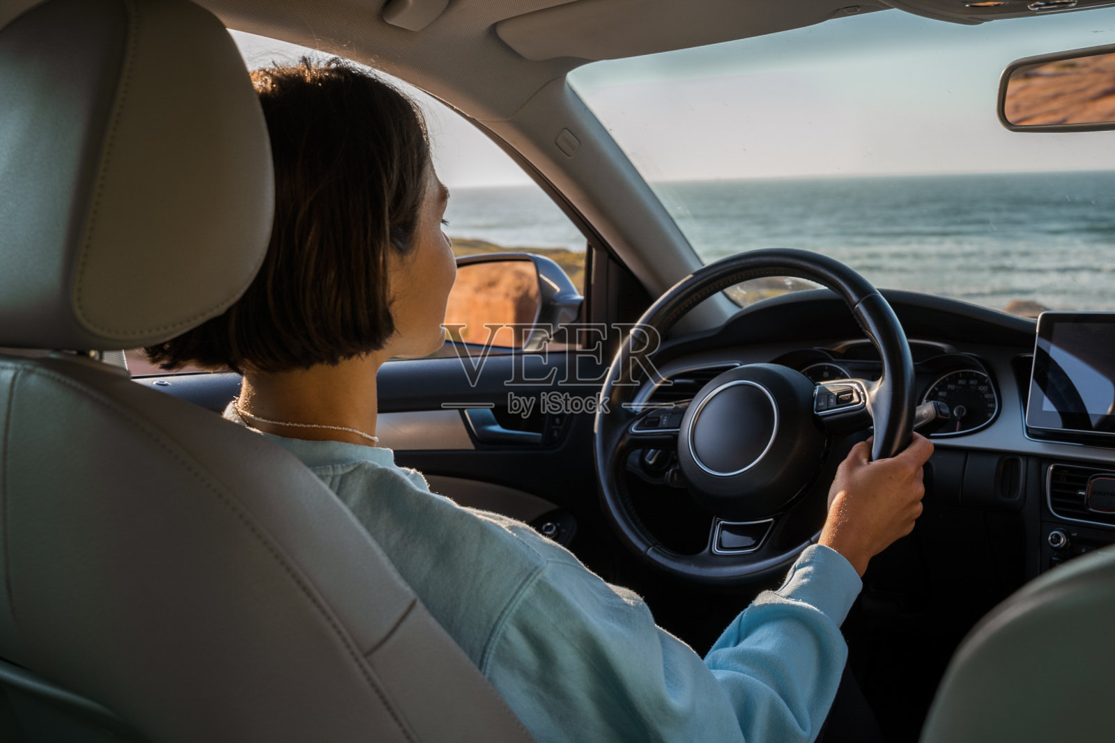女人坐在车里，骑车去新的地方，同时穿过海滨照片摄影图片