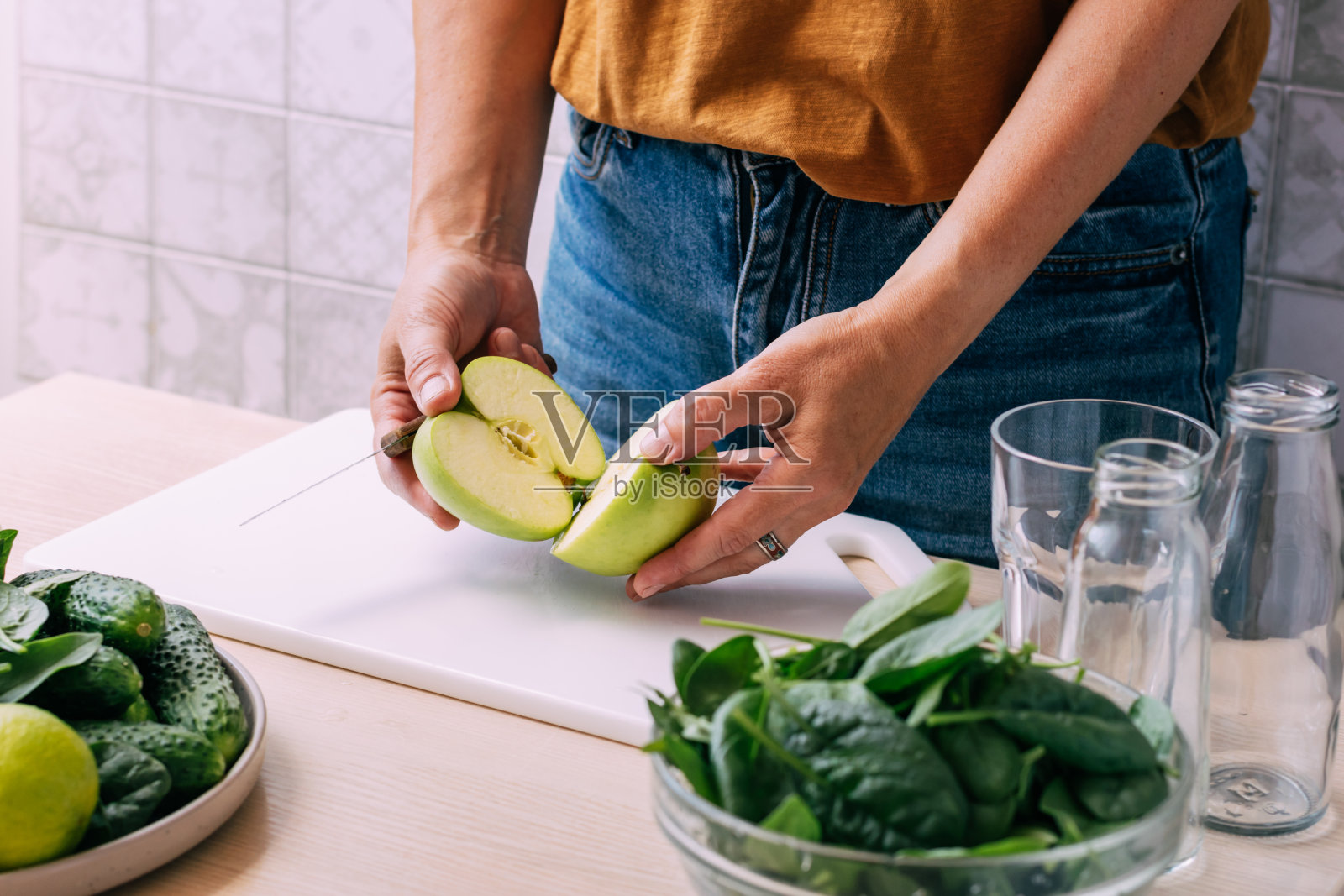 一名妇女用新鲜的水果和蔬菜准备一种绿色的奶昔饮料，烹饪的过程照片摄影图片