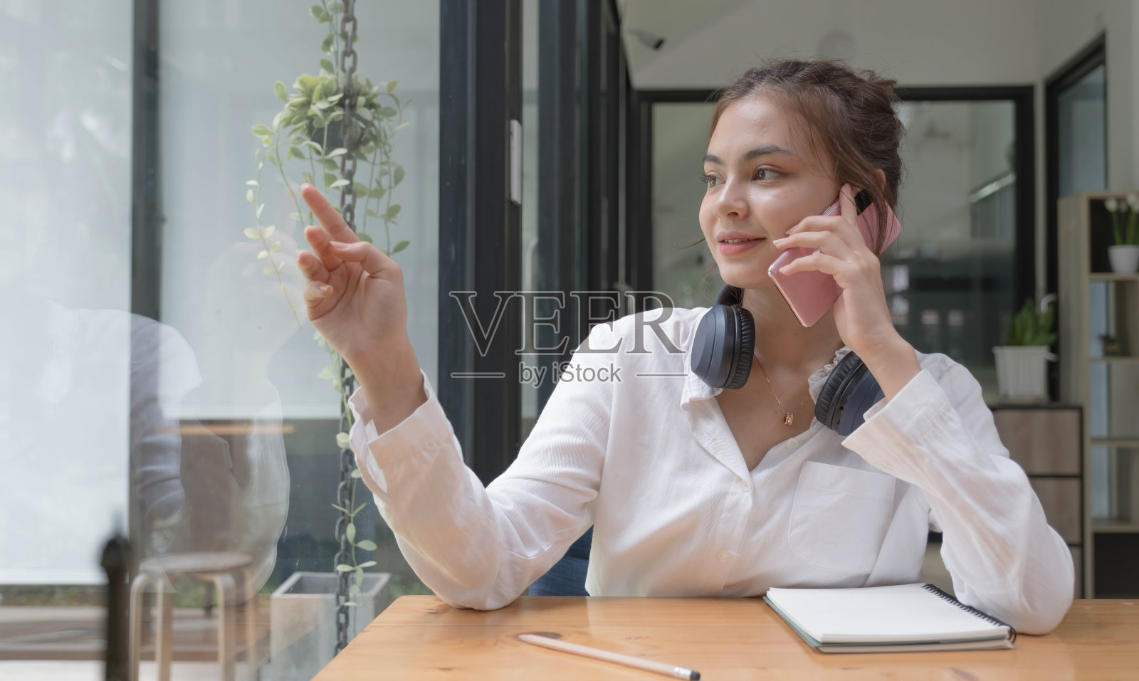 快乐的年轻亚洲十几岁的女孩坐在家里的沙发上拿着手机看屏幕挥手视频呼叫远方的朋友在线在移动聊天应用程序使用智能手机视频聊天应用程序。照片摄影图片
