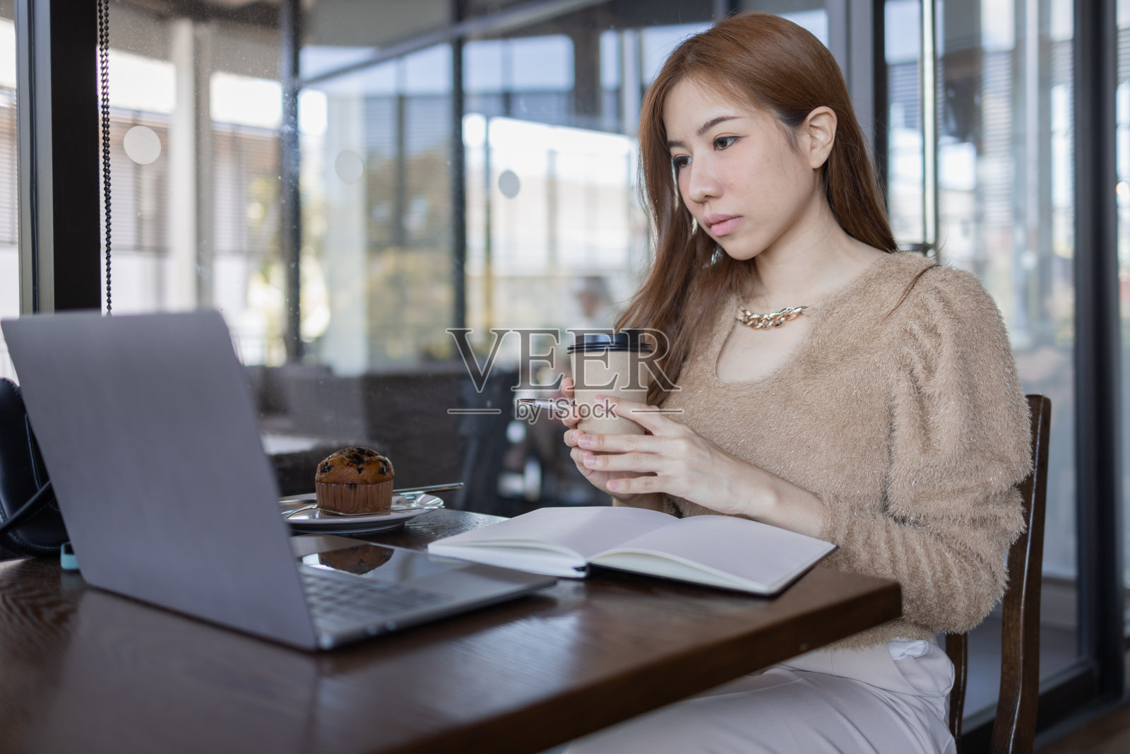 自由职业者商业亚洲妇女或研究在线亚洲女学生喝咖啡，做艰苦的工作在咖啡馆。照片摄影图片
