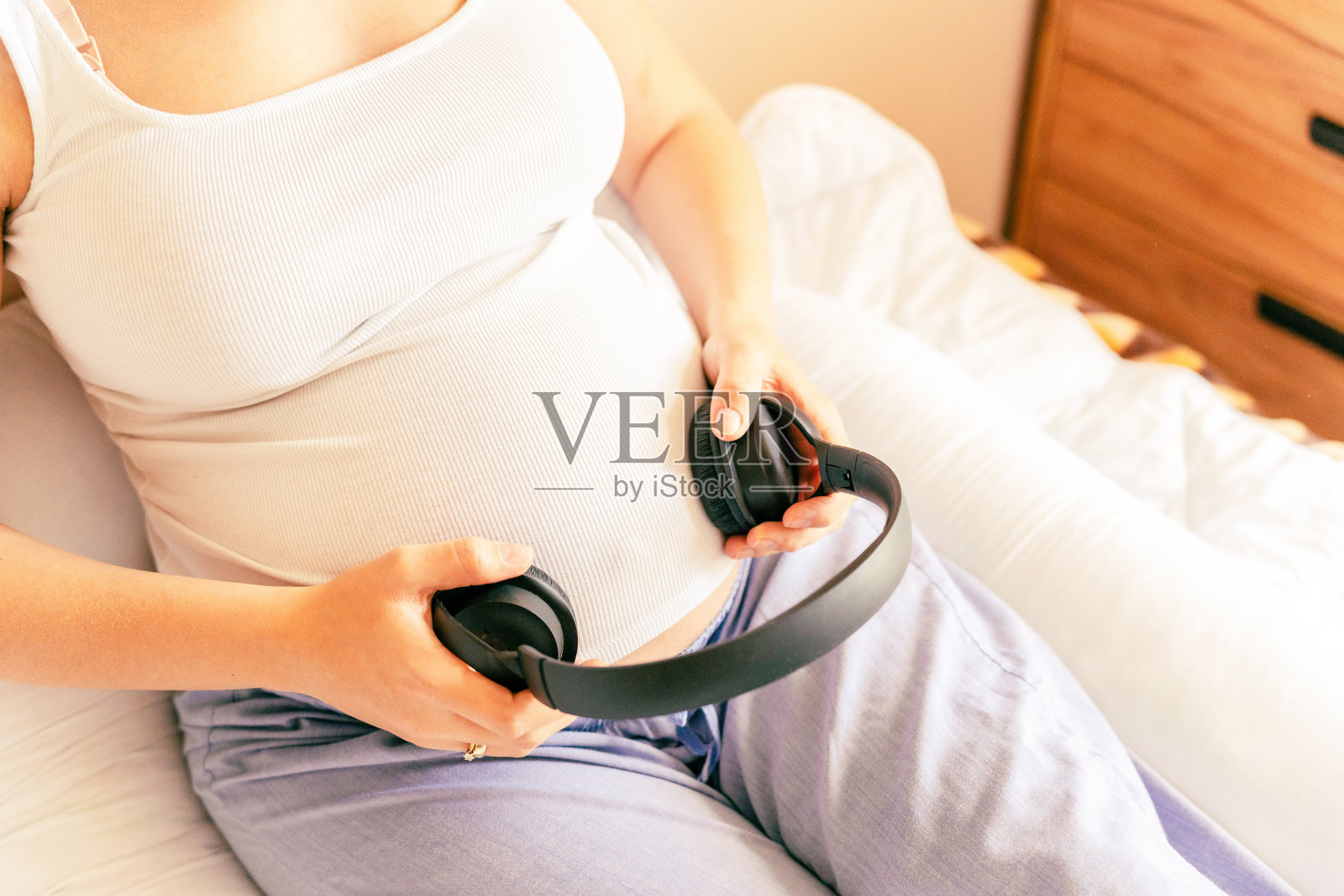 怀孕治疗音乐。听音乐的孕妇。妈妈肚子听耳机的声音。孕产期、医药保健和人的观念。照片摄影图片