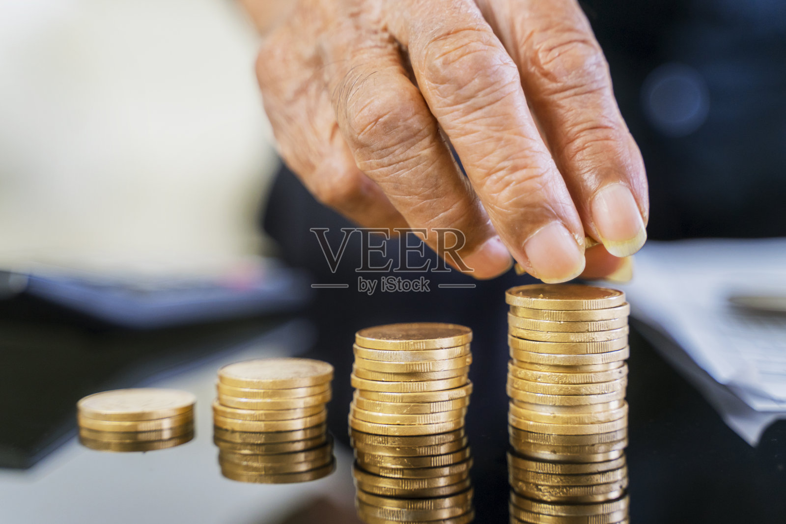 一位老人用手把金币堆叠在桌子上照片摄影图片