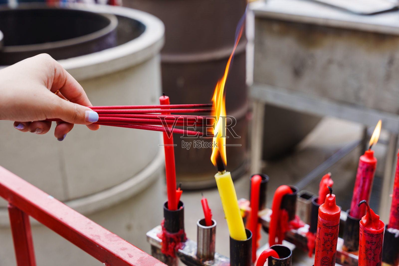 手牵手在庙里用蜡烛的火焰点燃红色的香照片摄影图片