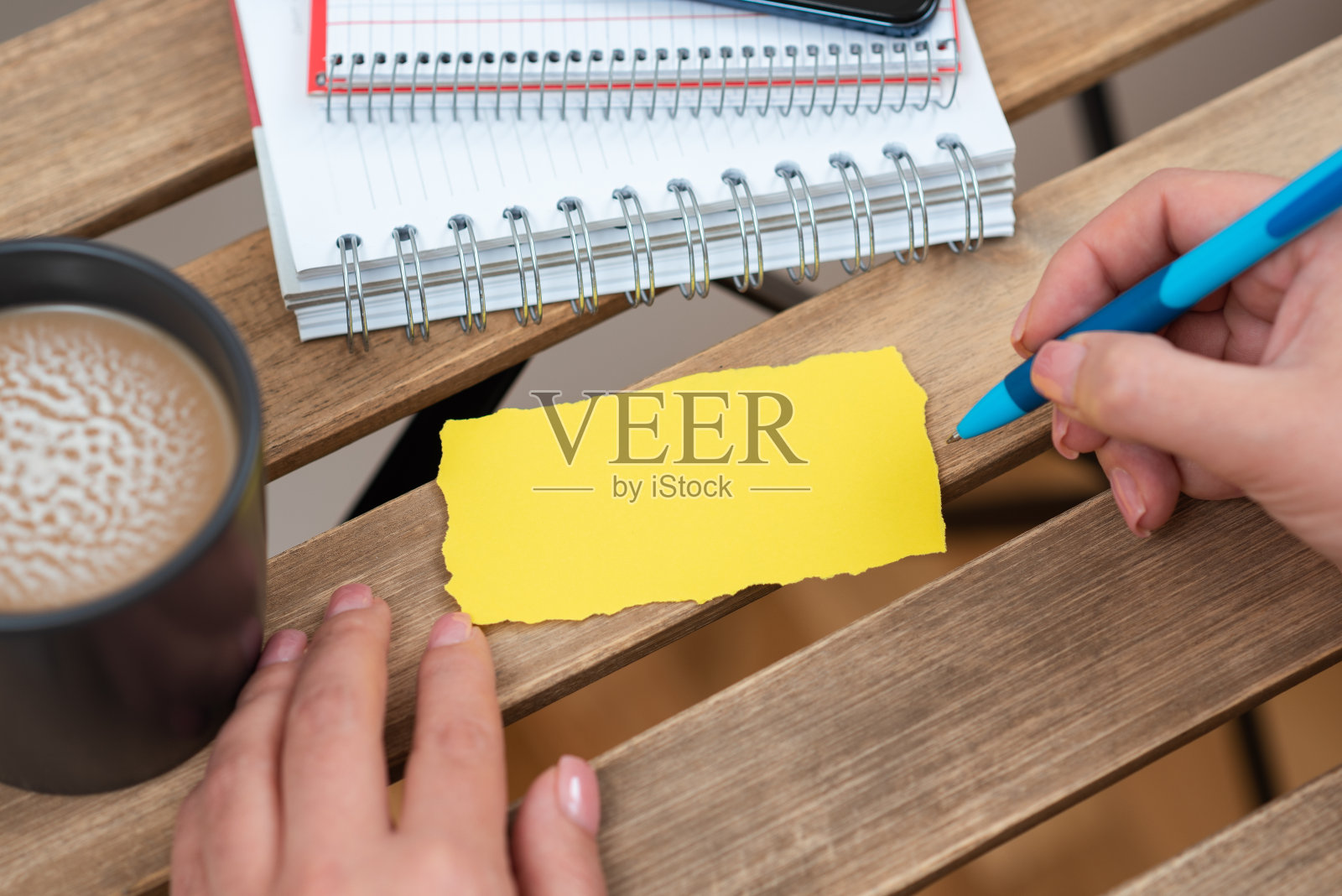 女商人拿着笔，在桌子上用咖啡和笔记本指着重要的信息。女人在桌上喝咖啡，把重要信息写在纸上。照片摄影图片