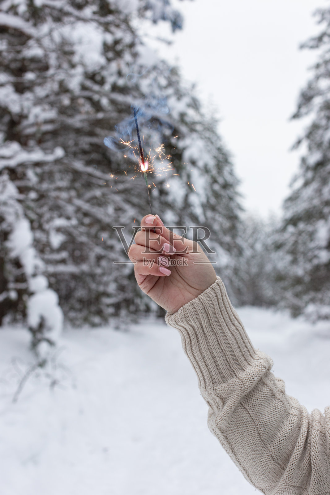 在冬日森林的背景下，一名妇女手拿烟火照片摄影图片