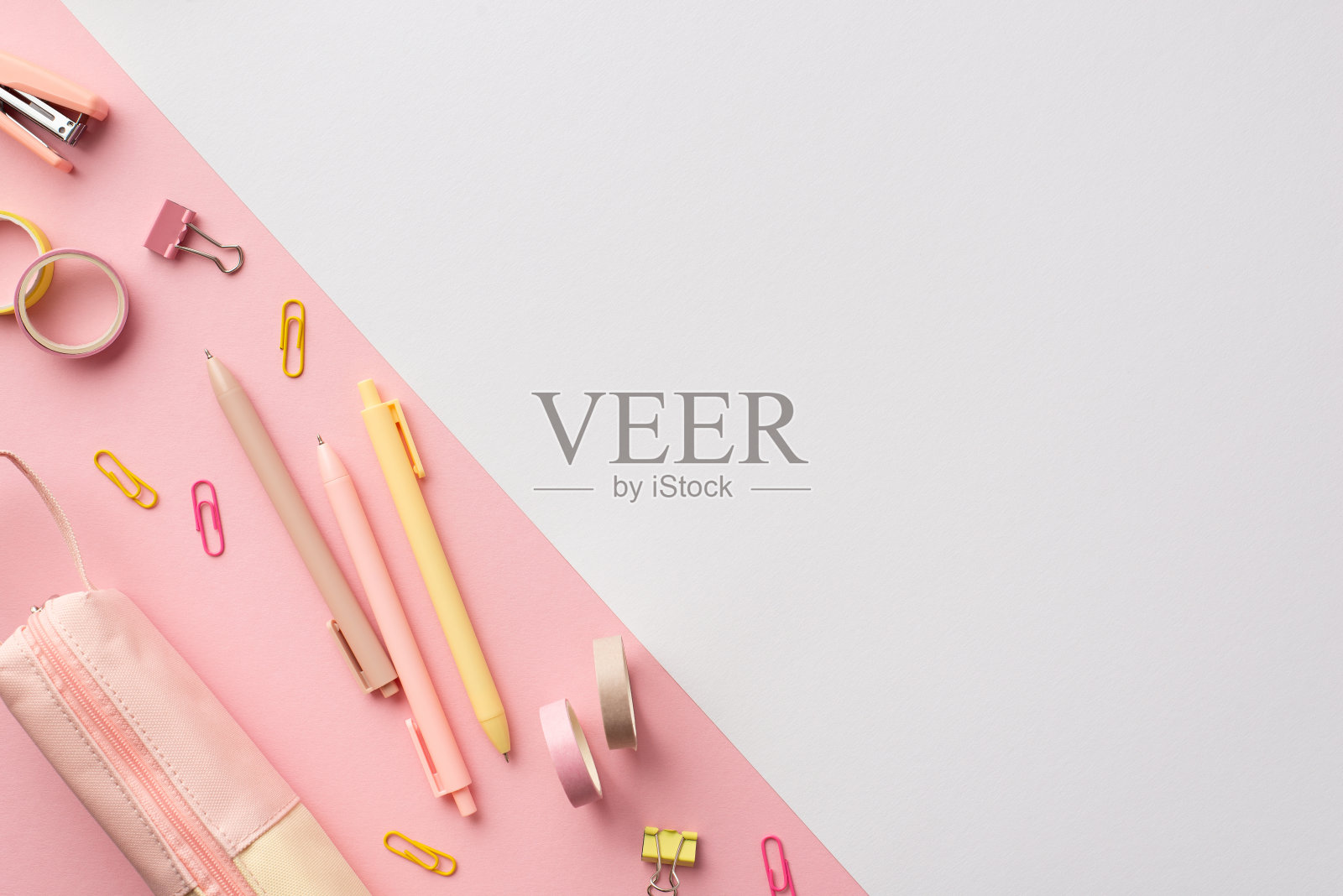 学校附件的概念。俯视图照片的粉红色和黄色文具笔迷你订书机活页夹胶带和铅笔盒在双色粉红色和白色的背景与copyspace照片摄影图片