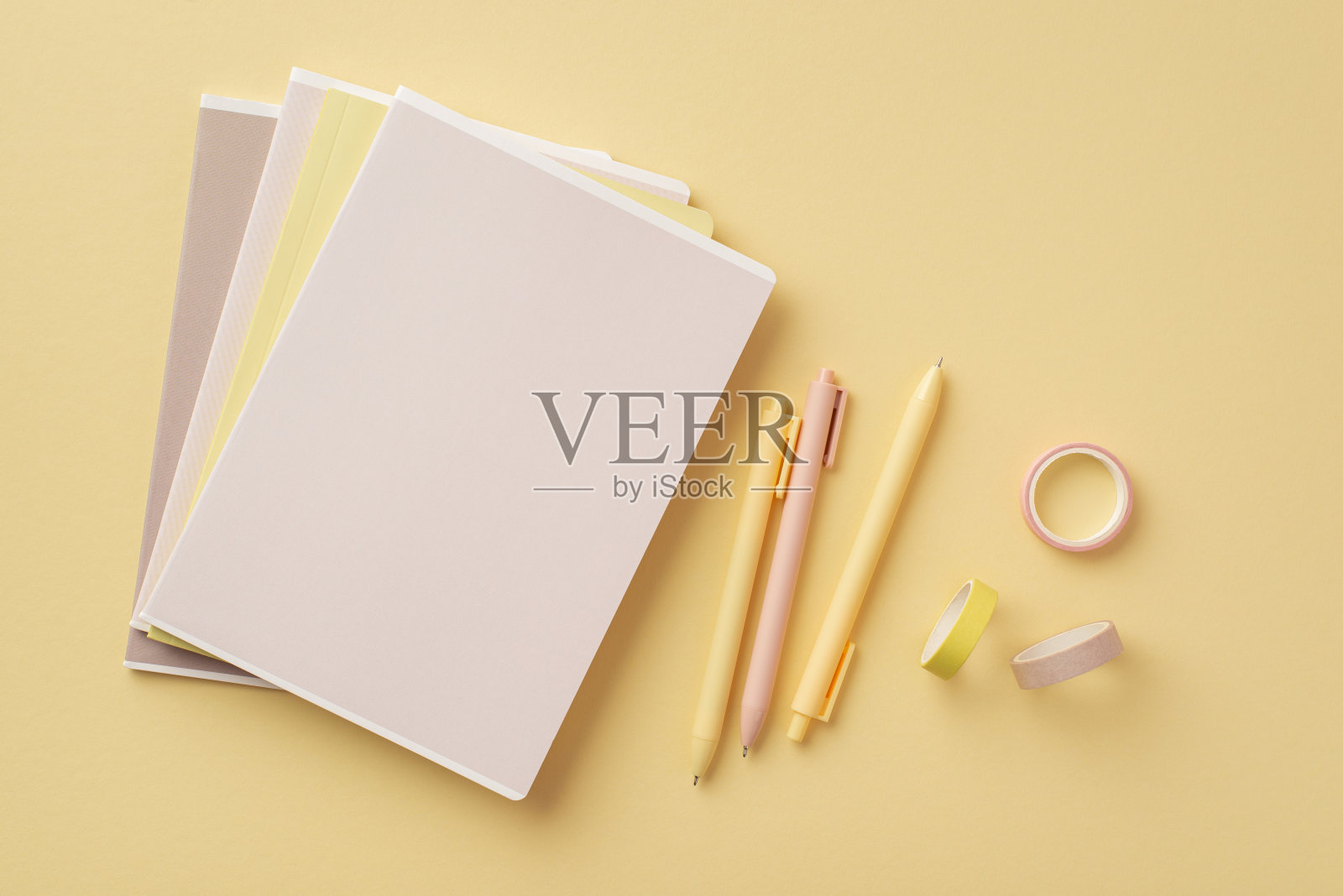 学校附件的概念。顶视图照片的文具copybooks胶布和笔在孤立粉彩黄色背景照片摄影图片
