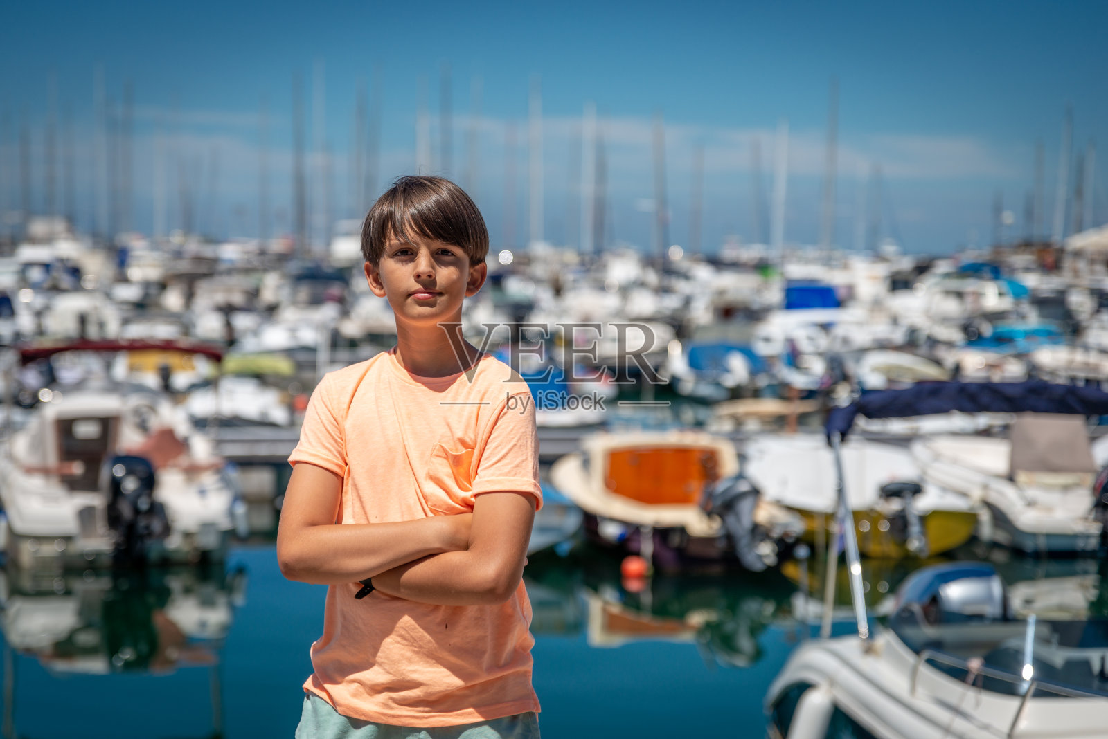 一个男孩看着停泊在港口的船只。照片摄影图片