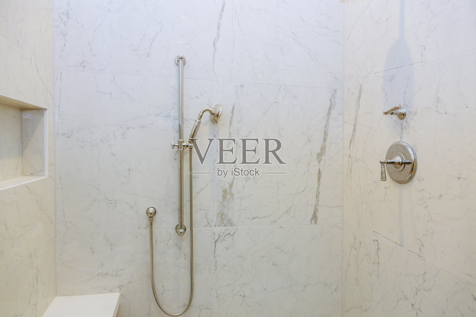 在一所新建筑的现代浴室里，浴缸前面有一个淋浴头照片摄影图片