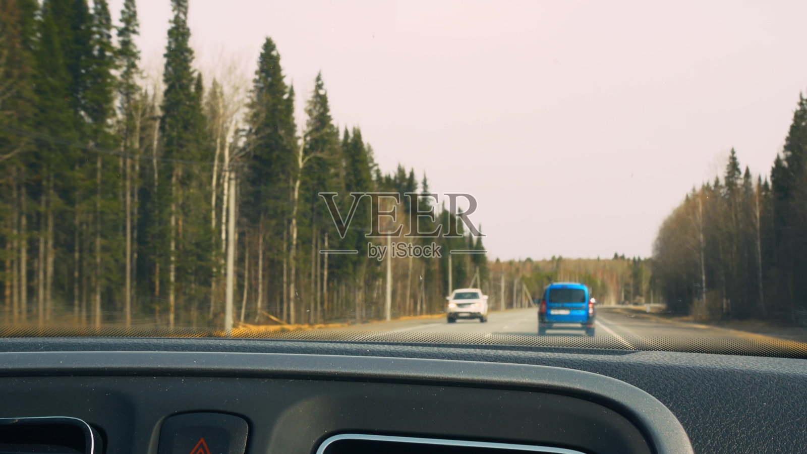 第一人称视角，从乘客车厢的汽车在道路上行驶的方向。FPV在高速公路上行驶时看挡风玻璃，路边是混交林。照片摄影图片