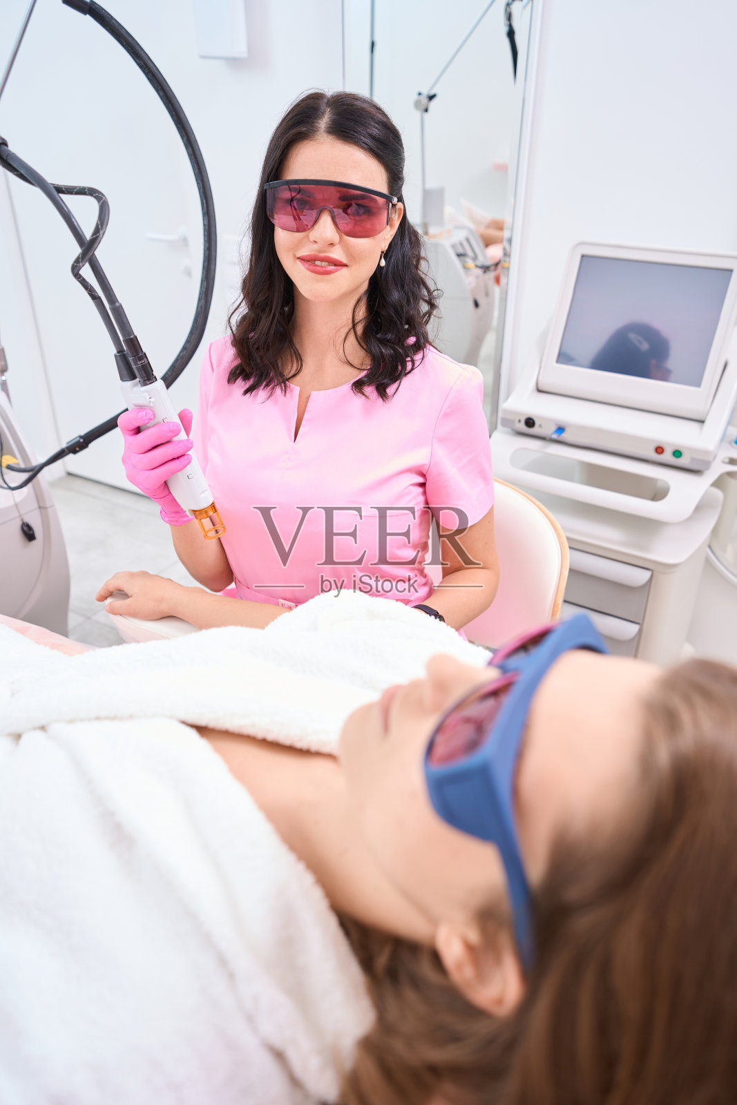 身着制服的美容师在客户旁边进行硬件操作照片摄影图片