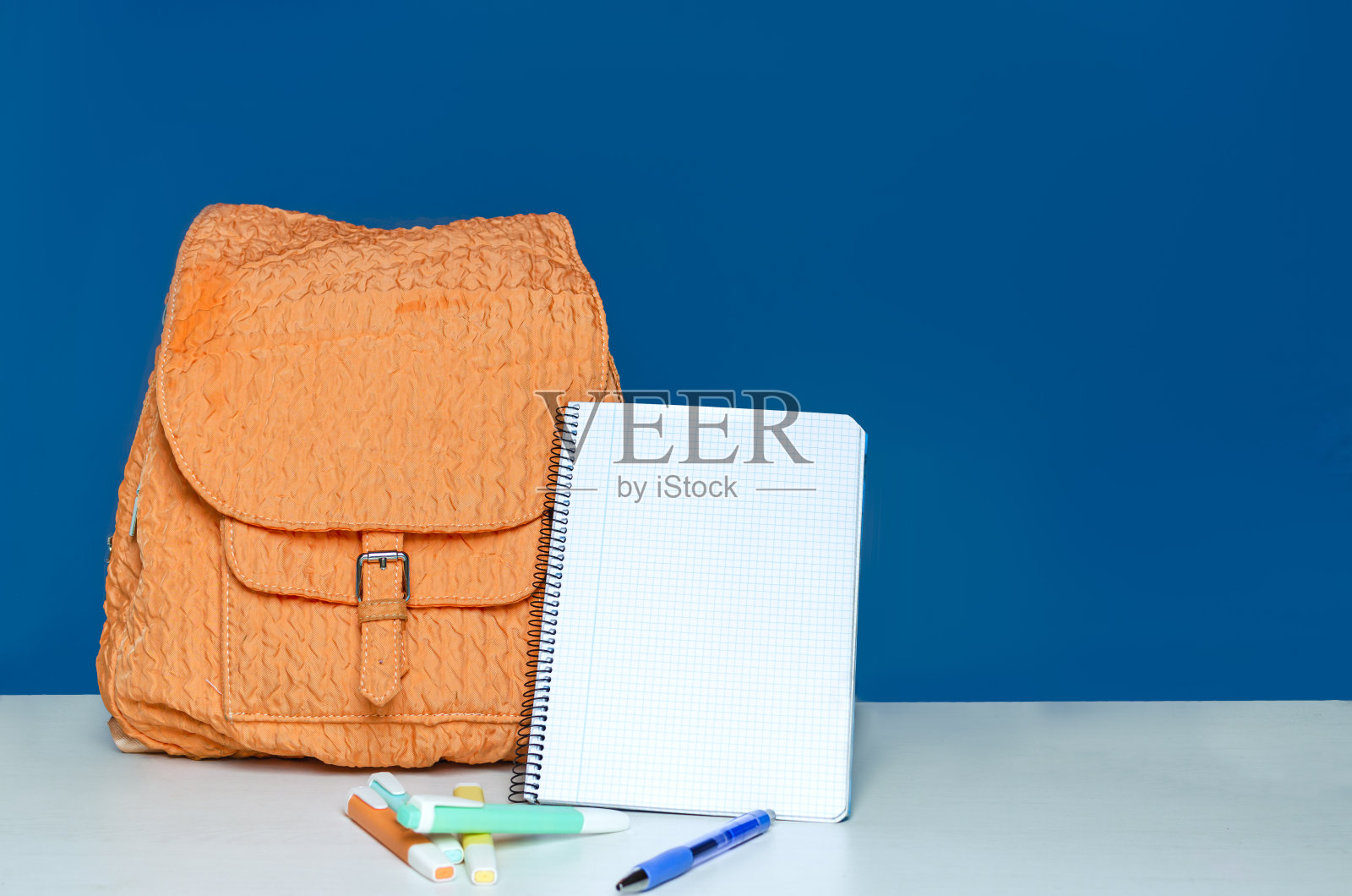 蓝色背景的橙色背包和笔记本照片摄影图片