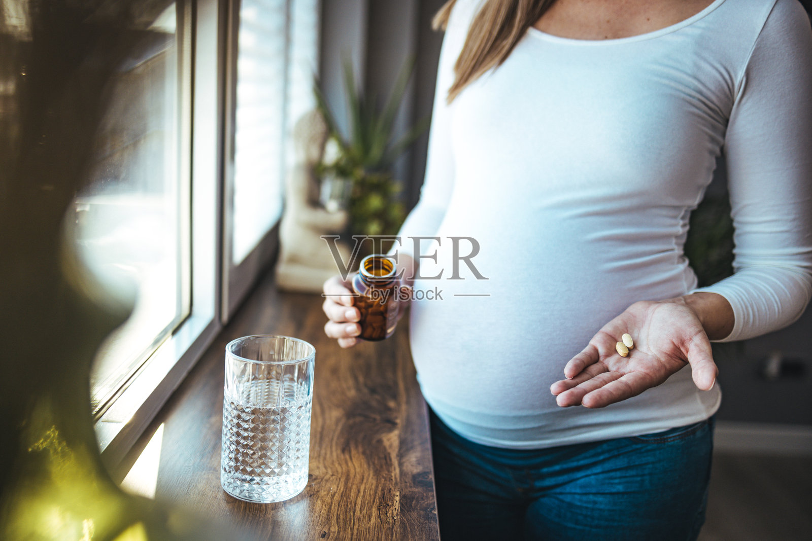 幸福女人端着药丸杯水，每天吃药维他命照片摄影图片
