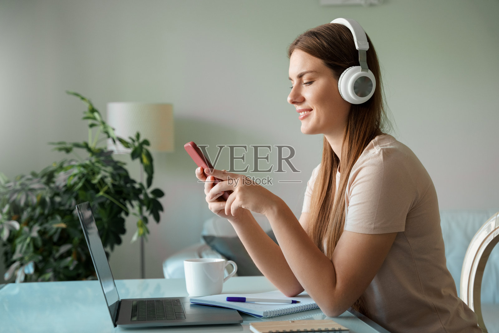 年轻的少女在工作或学习时戴着耳机使用智能手机照片摄影图片